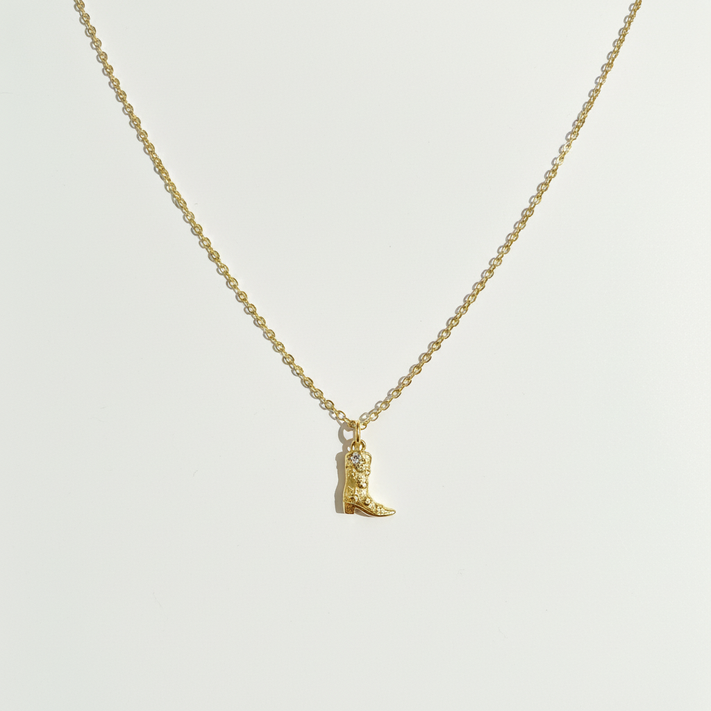 Cowboy boot necklace on white surface