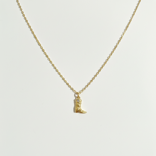 Cowboy boot necklace on white surface