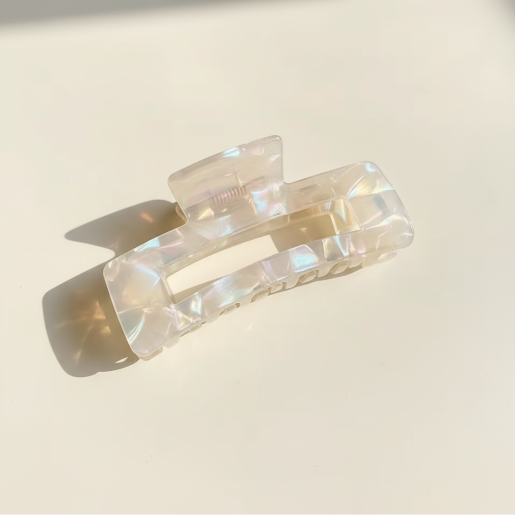 Clear iridescent rectangular hair claw clip on warm ivory background