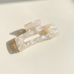Clear iridescent rectangular hair claw clip on warm ivory background