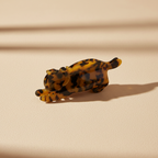 Tortoiseshell cat hair claw clip on warm beige surface