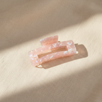 Pink iridescent rectangular hair claw clip on cream linen