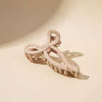 Medium beige bow hair claw clip on warm ivory background