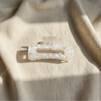 Clear iridescent rectangular hair claw clip on natural linen