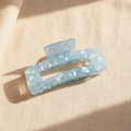 Blue iridescent rectangular hair claw clip on cream linen