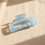 Blue iridescent rectangular hair claw clip on cream linen