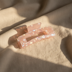 Pink iridescent rectangular hair claw clip on natural linen