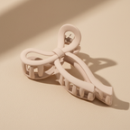 Medium beige bow hair claw clip on warm beige surface