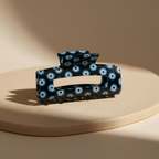 Black evil eye hair claw clip on warm beige surface