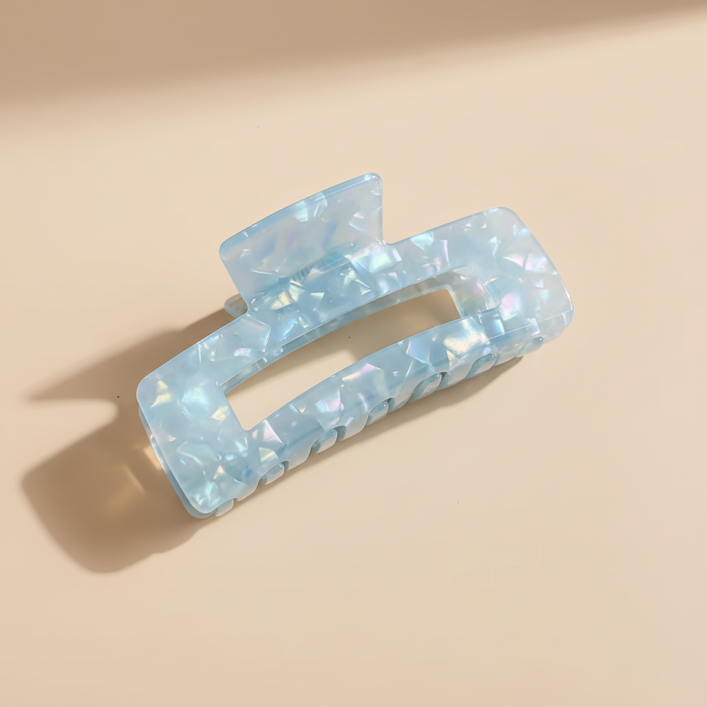 Blue iridescent rectangular hair claw clip on warm beige surface