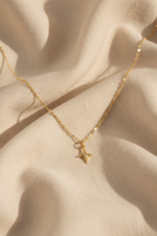 North star necklace on cream linen